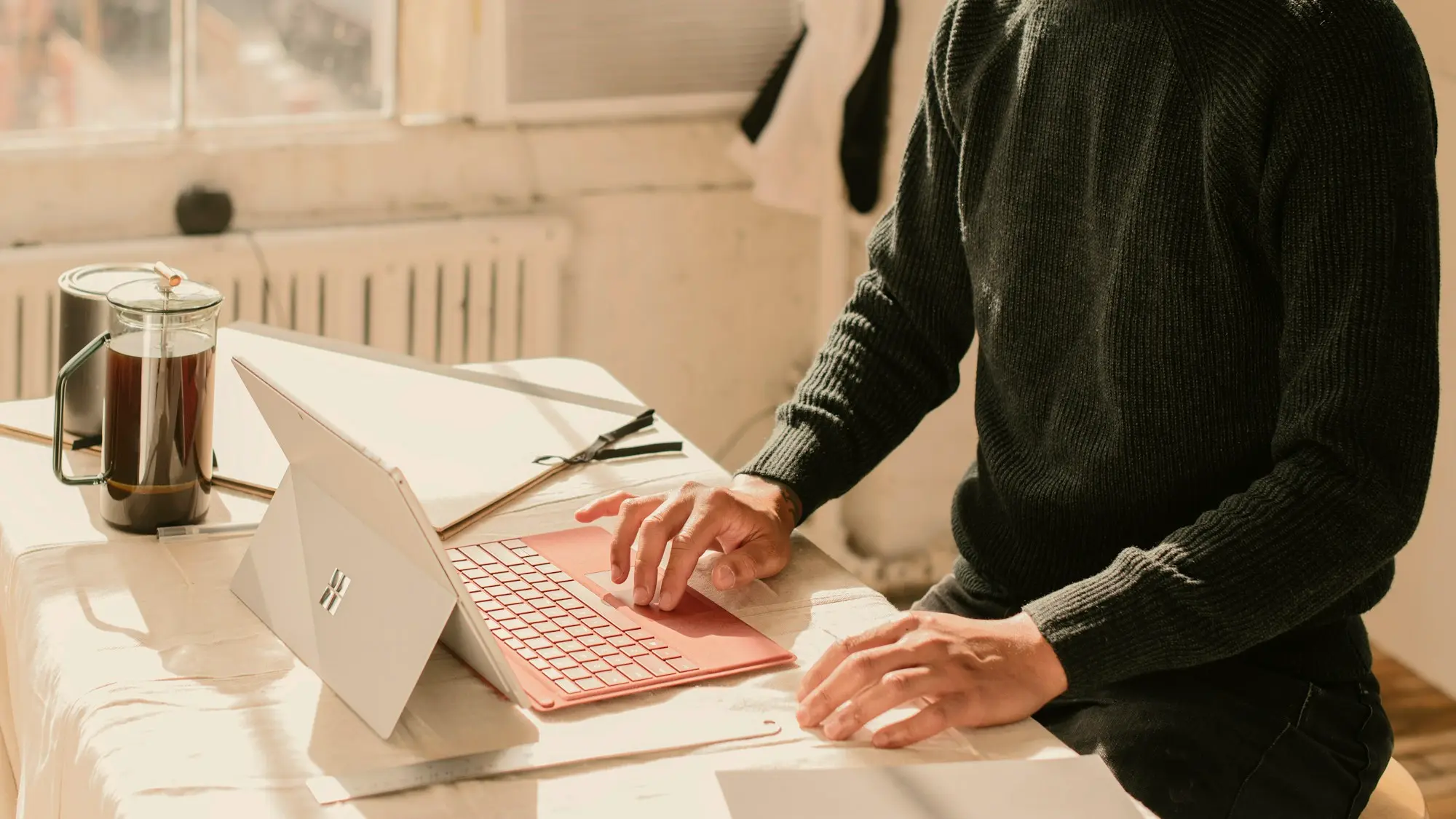 Osoba pracująca na laptopie przy biurku w jasnym pomieszczeniu